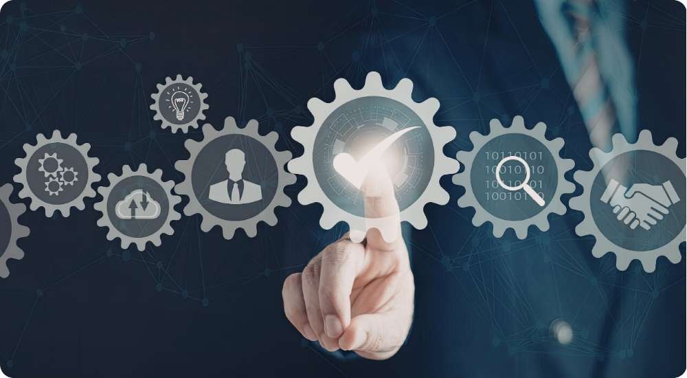 A close up photograph of a business person's hand interacting with a digital interface of interconnected gears, which feature icons for ideas, cloud data, business roles, and a handshake, symbolizing systematic and scalable hiring processes.