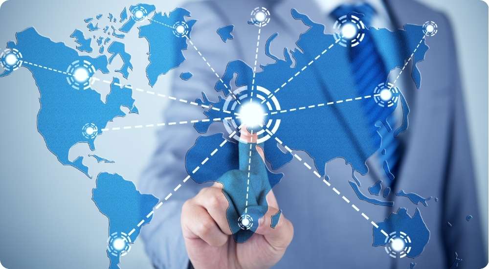 A close-up photograph of a business professional pointing a finger at a glowing network hub overlaid on a digital world map, symbolizing the challenges of managing global compliance.