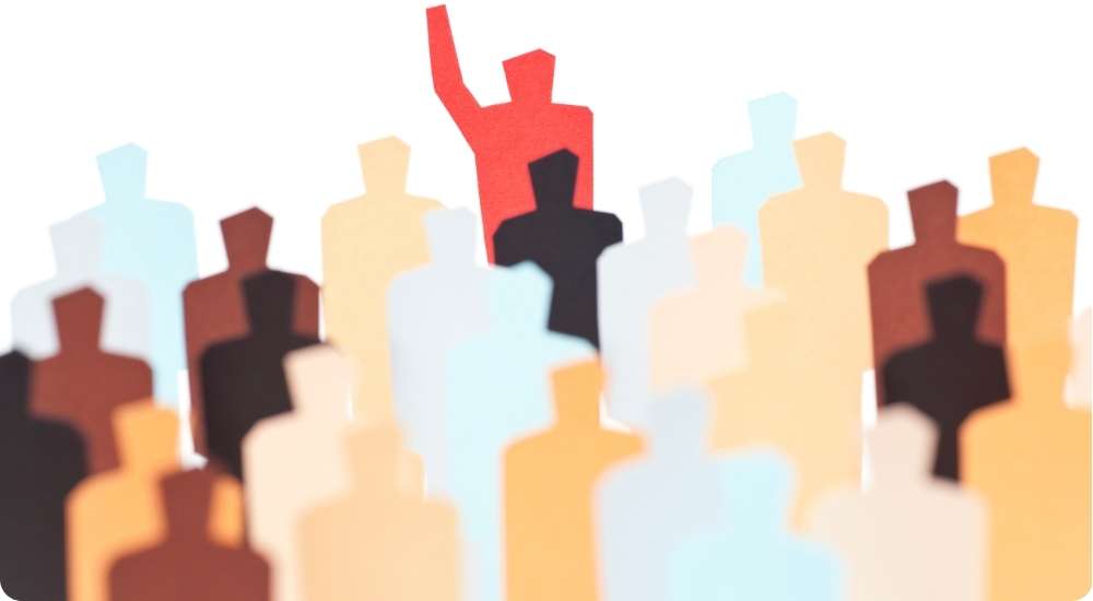 An illustration of a diverse crowd of stylized human silhouettes, with one red figure standing out from the rest with a raised hand, symbolizing leadership and unique talent.