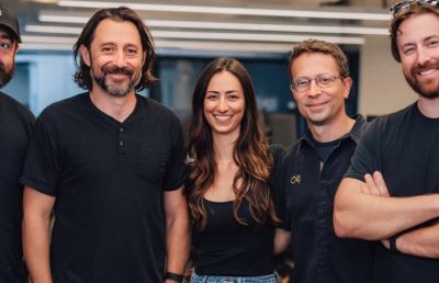 A diverse group of five smiling professionals standing together in a modern office environment, symbolizing a cohesive team balancing innovation and stability.
