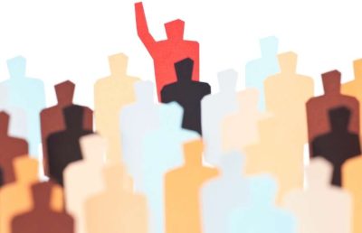 An illustration of a diverse crowd of stylized human silhouettes, with one red figure standing out from the rest with a raised hand, symbolizing leadership and unique talent.