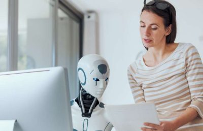 A professional woman in an office setting collaborates with a white humanoid robot, reviewing documents together, symbolizing the integration of human judgment in AI-powered recruitment processes.